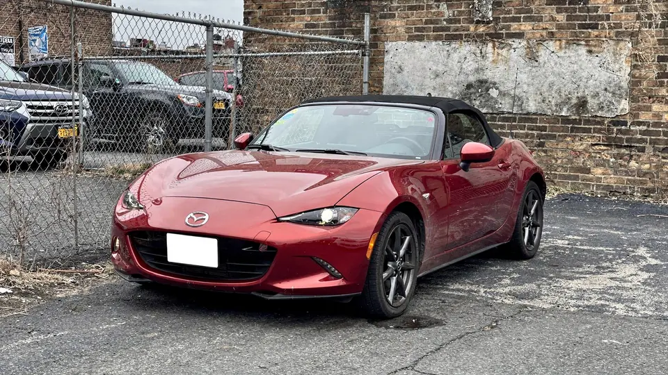 Red Mazda MX-5 Miata convertible parked on the lot (AI placeholder photo)